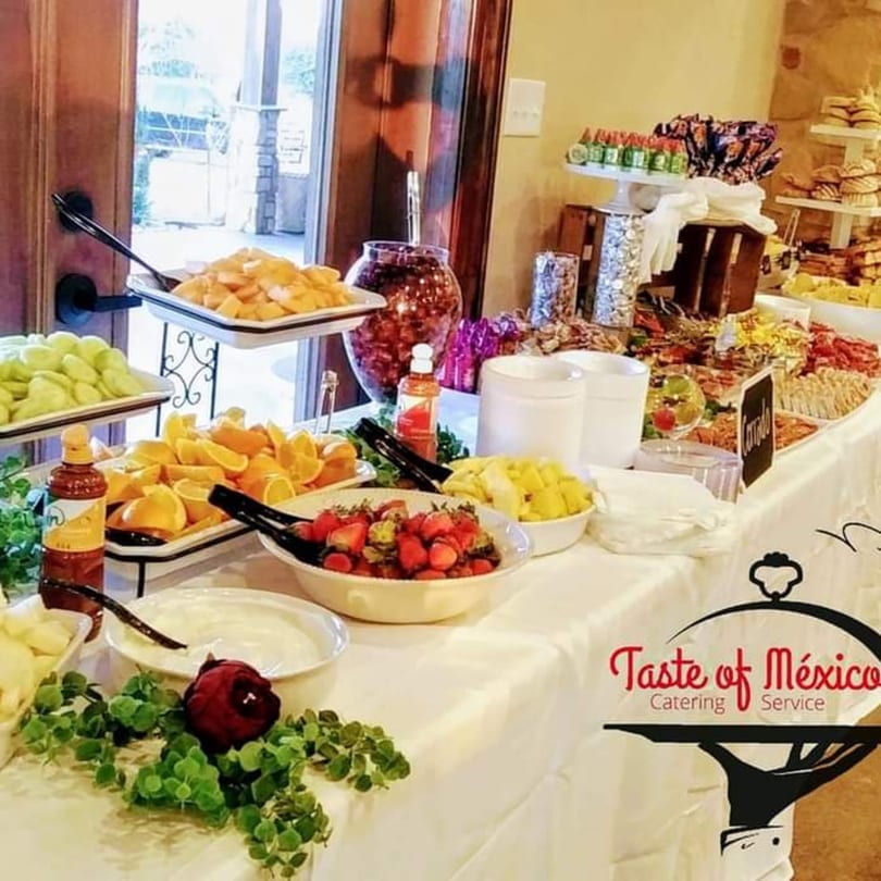 A buffet table from Taste of Mexico Catering Service, laden with fresh fruit, snacks, and sauces.